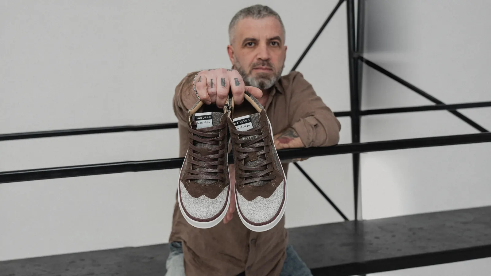 A man holding up a pair of Babylon sneakers