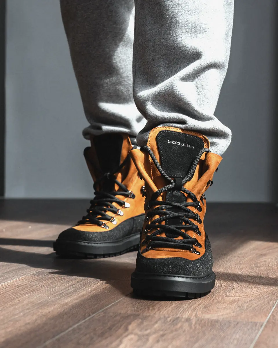 Brown leather Babylon Armor-24 lace-up boots worn with grey joggers, front view on a wooden floor