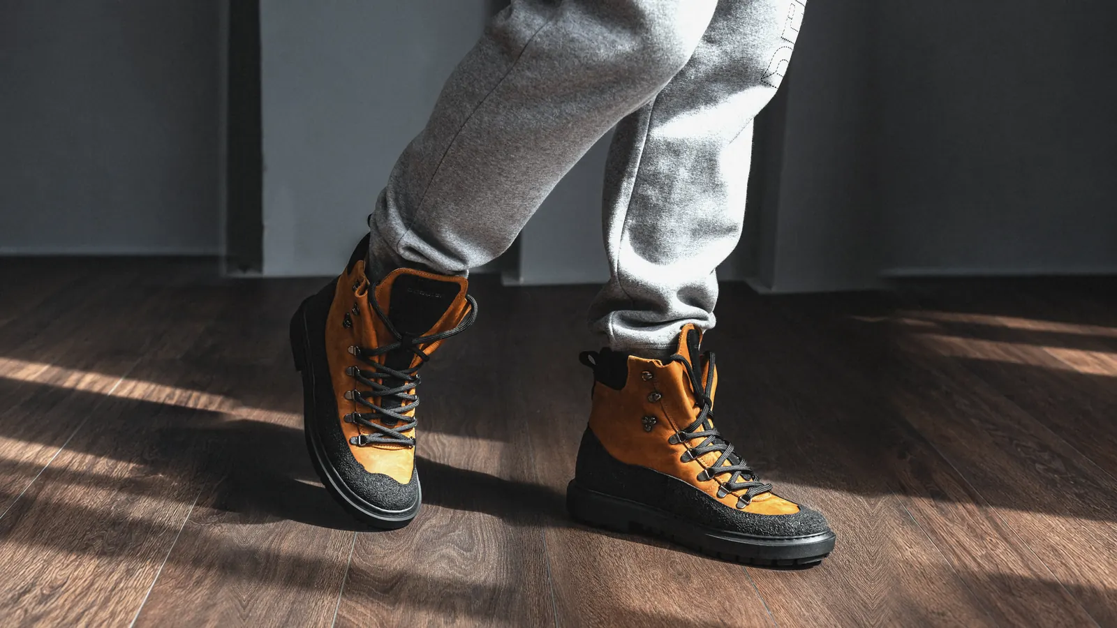 Babylon Armor-24 men's lace-up winter boots in brown and black leather, worn with grey joggers on a wooden floor
