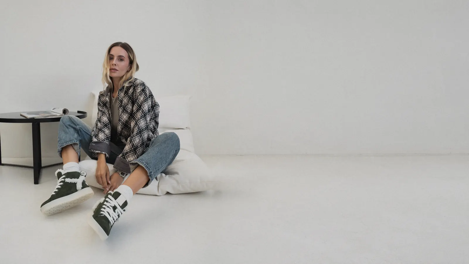 A woman in green suede Babylon sneakers in a bright studio