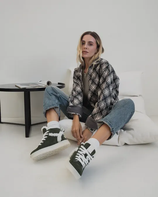 A woman in green suede Babylon sneakers in a bright studio
