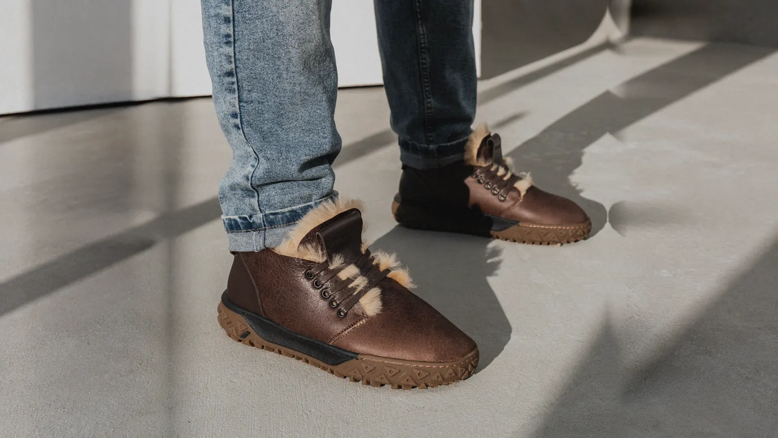 Brown fur-lined Babylon leather boots and jeans on a concrete floor