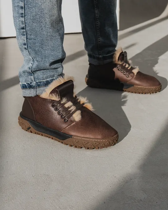 Brown fur-lined Babylon leather boots and jeans on a concrete floor