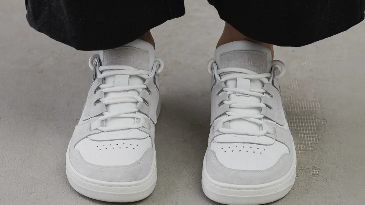 White and light grey women's Space-90 sneakers in combination leather, worn with black cuffed jeans, front view of the pair
