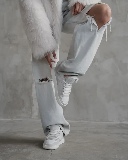 White Babylon leather sneakers with wide-leg jeans on a concrete floor
