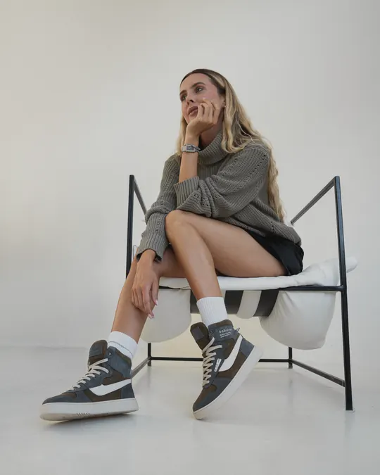 A woman in a chair showing her Babylon high-top sneakers in a bright studio