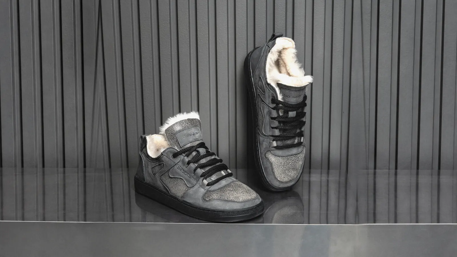 A pair of grey fur-lined Babylon Space-02-D sneakers on a metal shelf against dark panelling