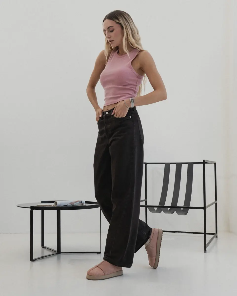 Woman in wide dark jeans and a pink top standing in powder-pink nubuck MARY-99 slip-ons with a light sole, full-length view