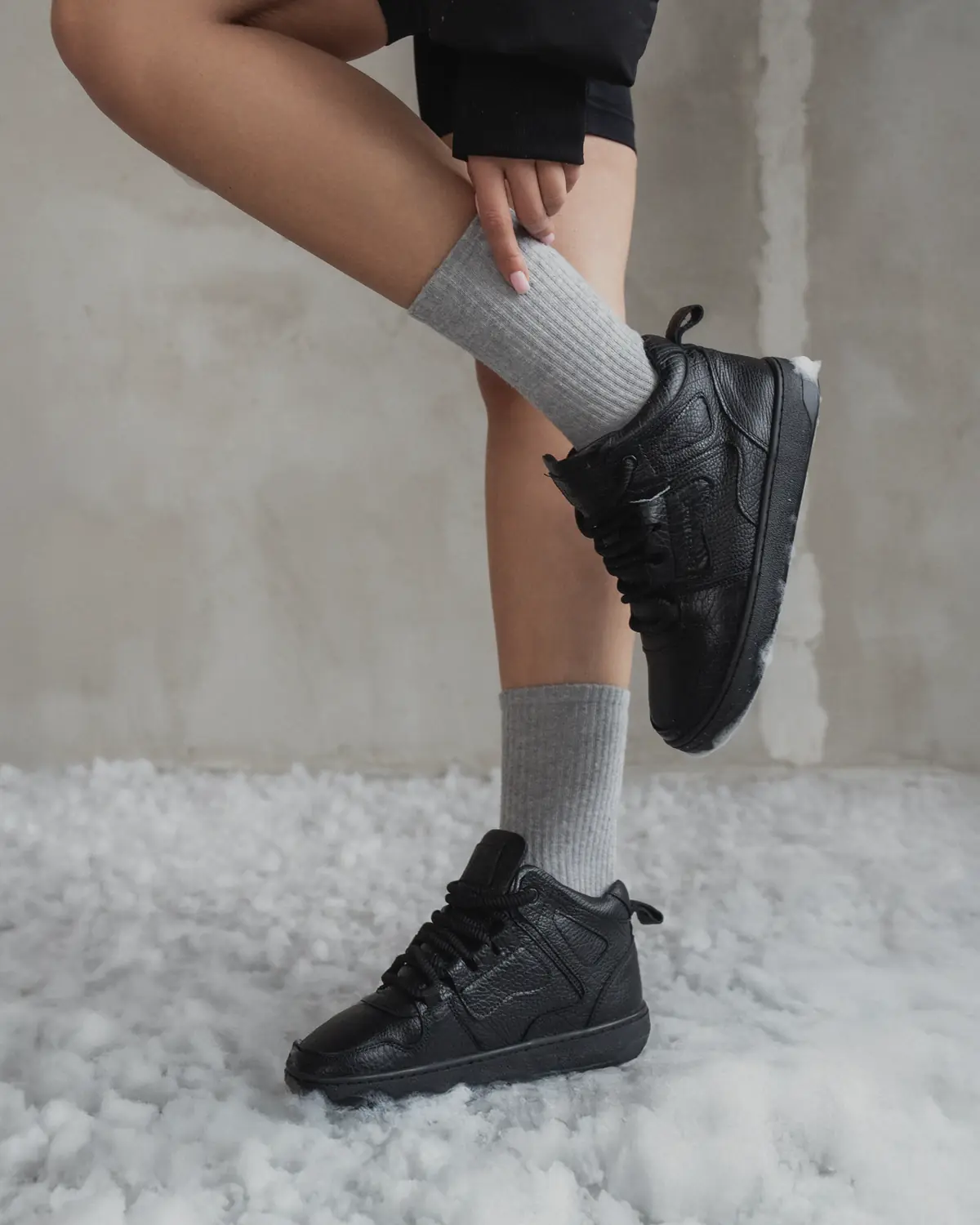 Babylon Space-81-X women's black leather high-top sneakers worn with grey socks, one foot standing in snow